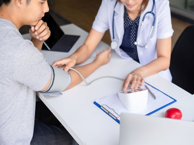 Blutdruckmessung bei einem Patienten während eines Arztbesuchs.